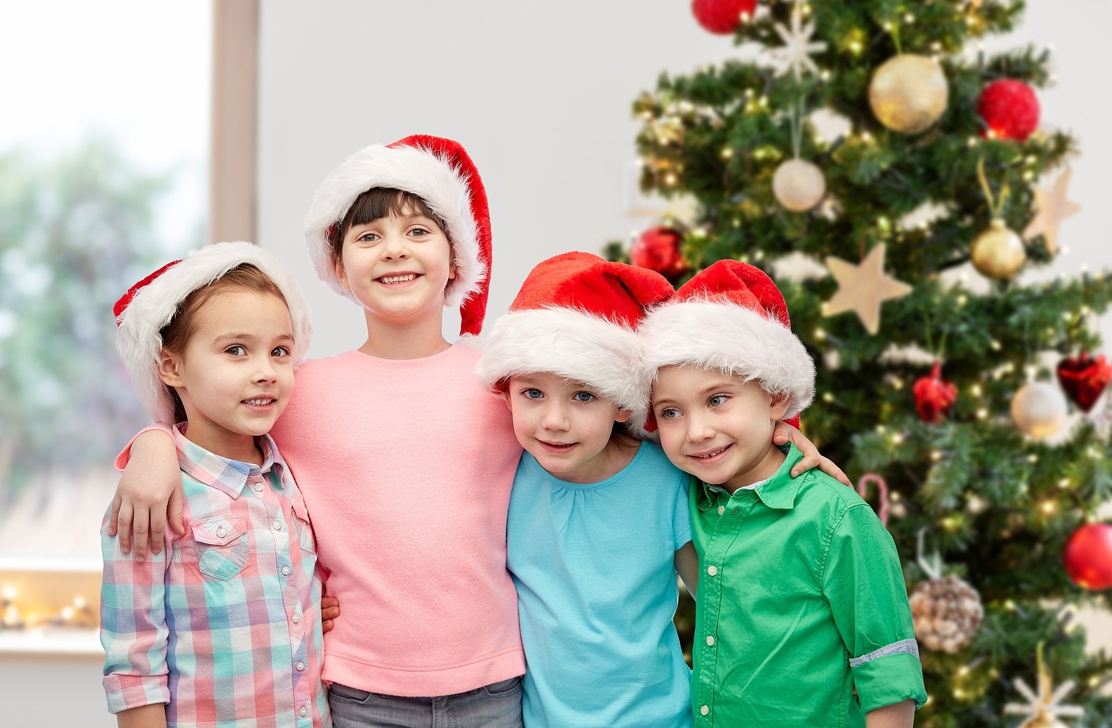 Four festive children in front of a Christmas tree