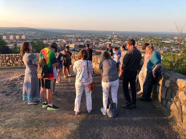 A group of adults and teens stands at the Garret Mountain overlook praying over the city of Paterson