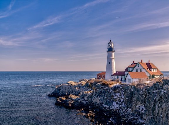 Daytime photo of a lighthouse on a rocky shore